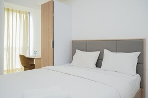 Relax in a serene space with a large bed, wooden desk, and ample natural light.