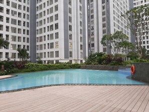 Enjoy a refreshing dip in the pool surrounded by lush greenery and a wooden deck.