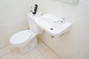 Bathroom features a toilet, sink with faucet and drain, and tiled walls.