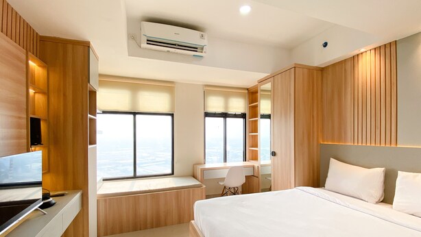 Ein modernes Schlafzimmer mit einem großen Bett, einem Schreibtisch und einem Fenster mit Blick.