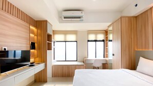 Ein modernes Hotelzimmer mit Bett, Schreibtisch, Fernseher und integrierten Schränken.