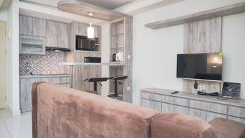 A modern kitchen with wooden cabinets, a microwave, a coffee maker, and a TV mounted on the wall.
