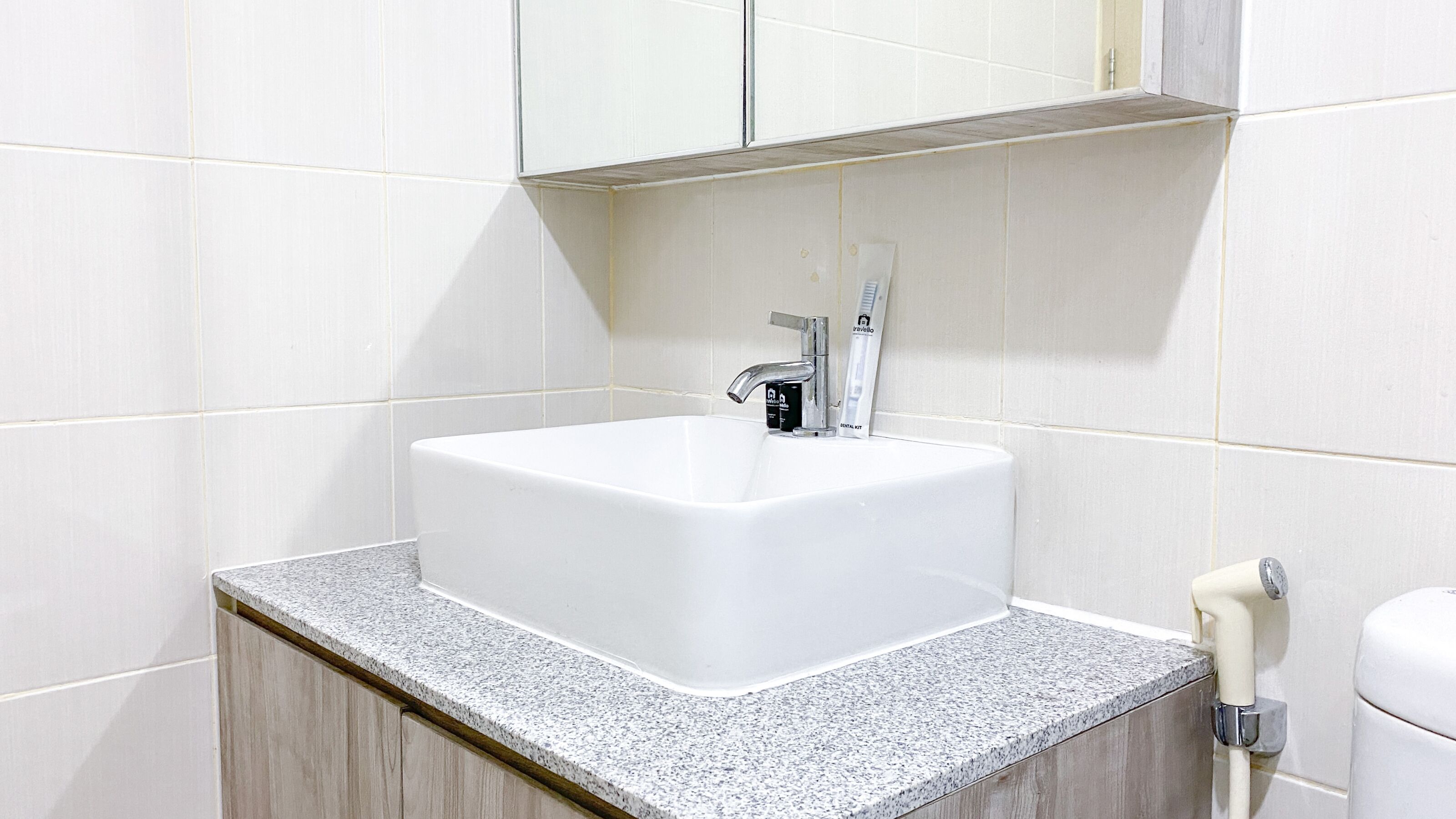Casa de banho com lavatório branco, espelho em cima e bancada.