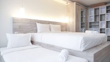 A hotel room with two beds, a wooden headboard, and a built-in wardrobe with glass doors.