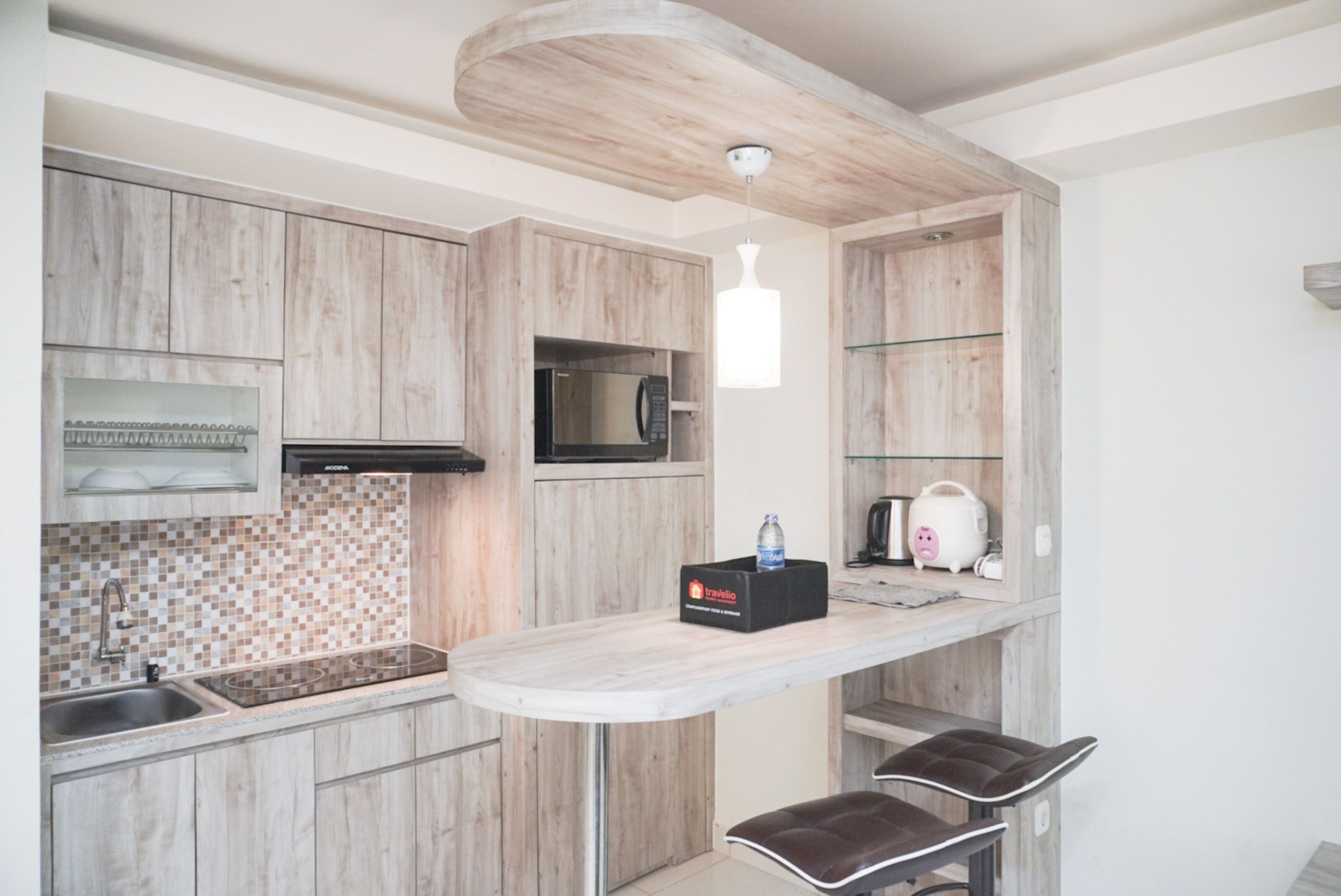 A modern kitchen with wooden cabinets, a microwave, a toaster, and a water dispenser on a countertop.
