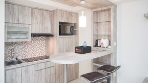 Una cocina moderna con armarios de madera, microondas, tostadora y dispensador de agua sobre una encimera.