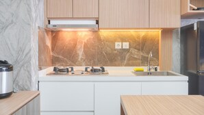 Een moderne keuken met witte kasten, een marmeren spatwand en roestvrijstalen apparatuur.