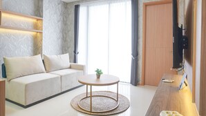 Een moderne woonkamer met een bank, een rond salontafeltje en een aan de muur bevestigde televisie.