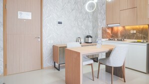 Een moderne keuken met een houten tafel, twee stoelen, een waterkoker, een waterfles en een fornuis.