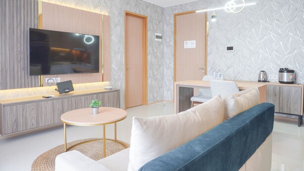 Een moderne woonkamer met een flatscreen-tv, een bank, een klein rond tafeltje en een keukenhoek met een waterkoker en een waterkoker.