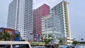 A multi-story building with a modern architectural design, featuring a mix of glass and concrete facades. - Homey Studio Room At Taman Melati Margonda Apartment (Depok)