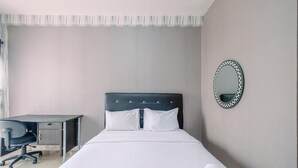 A hotel room with a bed, a desk, and a chair. - Homey Studio Room At Taman Melati Margonda Apartment (Depok)