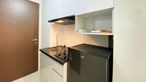 A compact kitchen with white cabinets, a black refrigerator, and a stainless steel sink. - Nice And Cozy Studio At Transpark Juanda Bekasi Timur Apartment (Bekasi)