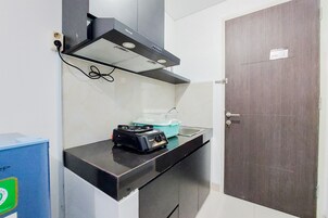 A kitchenette with a gas stove, a range hood, and a blue container on the counter.