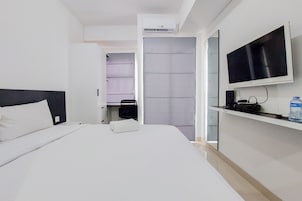 A modern hotel room with a large bed, a flat-screen TV mounted on the wall, and a water dispenser on the nightstand.