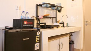 A kitchenette with a refrigerator, a coffee machine, and a dish rack. - Minimalist And Restful Studio Tokyo Riverside Pik 2 Apartment (Teluknaga)