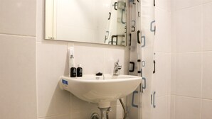 A bathroom with a white sink, mirror, and tiled walls. - Minimalist And Restful Studio Tokyo Riverside Pik 2 Apartment (Teluknaga)