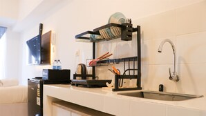 A modern kitchen with a built-in dishwasher, a sink with a faucet, and a dish rack above the counter. - Minimalist And Restful Studio Tokyo Riverside Pik 2 Apartment (Teluknaga)