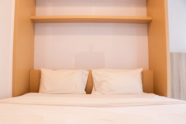 Cozy retreat with a single bed, simple headboard, and ample storage above.