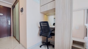 Ein Hotelzimmer mit Holztisch, schwarzem Bürostuhl, Bett und Kleiderschrank.