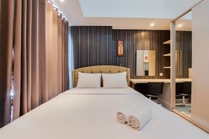 Ein Hotelzimmer mit einem großen Bett, einem Schreibtisch, einem Stuhl und einem Spiegel.