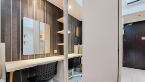 A modern bathroom with a large mirror, a white countertop, and two black chairs.