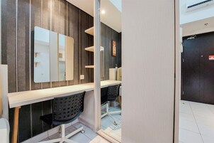 A modern bathroom with a large mirror, a white countertop, and two black chairs.