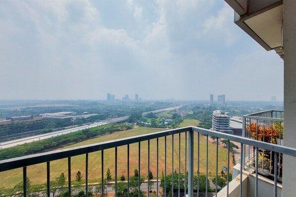 Un balcón con vista a un paisaje urbano, que incluye edificios y una autopista.