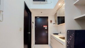 A narrow hallway with a dark door, a white sink, and a mirror above it.