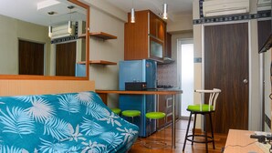 A compact kitchen with a blue refrigerator, wooden cabinets, and a bar stool. - Beautiful 2Br With Direct Access To Pool Green Bay Pluit Apartment (Jakarta)