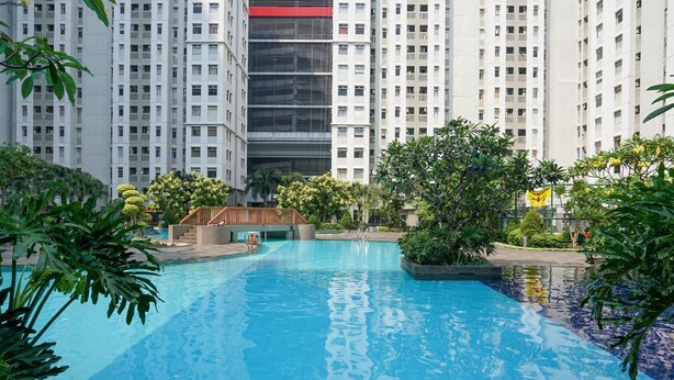 A swimming pool surrounded by greenery and tall buildings. - Beautiful 2Br With Direct Access To Pool Green Bay Pluit Apartment (Jakarta)