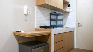 A compact kitchen with a wooden countertop, a GEA refrigerator, a blue rack, and a white wall socket.