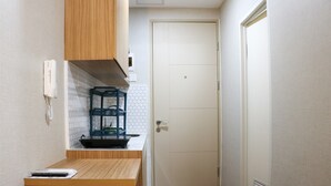 A narrow hallway with a wooden counter, a white door, and a white wall with a hexagonal pattern.