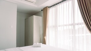 A hotel room with a bed, a wardrobe, and a window with sheer curtains. - Comfortable And Homey 2Br At Transpark Bintaro Apartment (South Tangerang)
