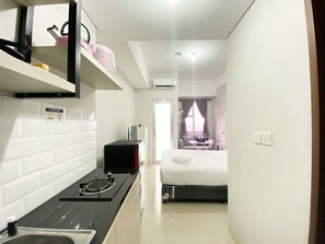 Cozy retreat with a kitchenette, featuring a stove, refrigerator, and microwave, plus a comfortable bed and small dining area.