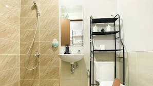 A bathroom with a shower, sink, toilet, and shelves.