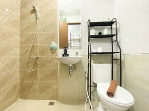Bathroom features a shower enclosure, sink, and toilet, along with storage and a potted plant.