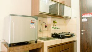 A kitchen with a refrigerator, stove, and cabinets. - Cozy Living Studio Room At Serpong Greenview Apartment (South Tangerang)