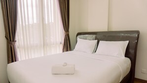 Un lit bien fait, avec du linge de lit blanc, un oreiller blanc et une table de chevet blanche sur laquelle se trouve une télécommande.