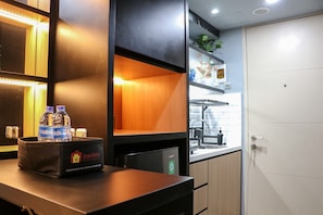 Een kitchenette met een aanrecht, een prullenbak met de tekst 'Travelio' en een waterdispenser.
