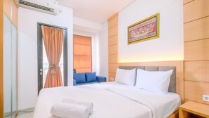 Una habitación de hotel con una cama, un sofá azul, un aire acondicionado de pared y una obra de caligrafía enmarcada en la pared.