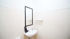 A clean bathroom with a sink and mirror, featuring a towel dispenser.