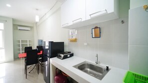 A modern kitchen with a white countertop, stainless steel sink, and black chairs. - Best Deal And Homey 2Br At Bale Hinggil Apartment (Surabaya)