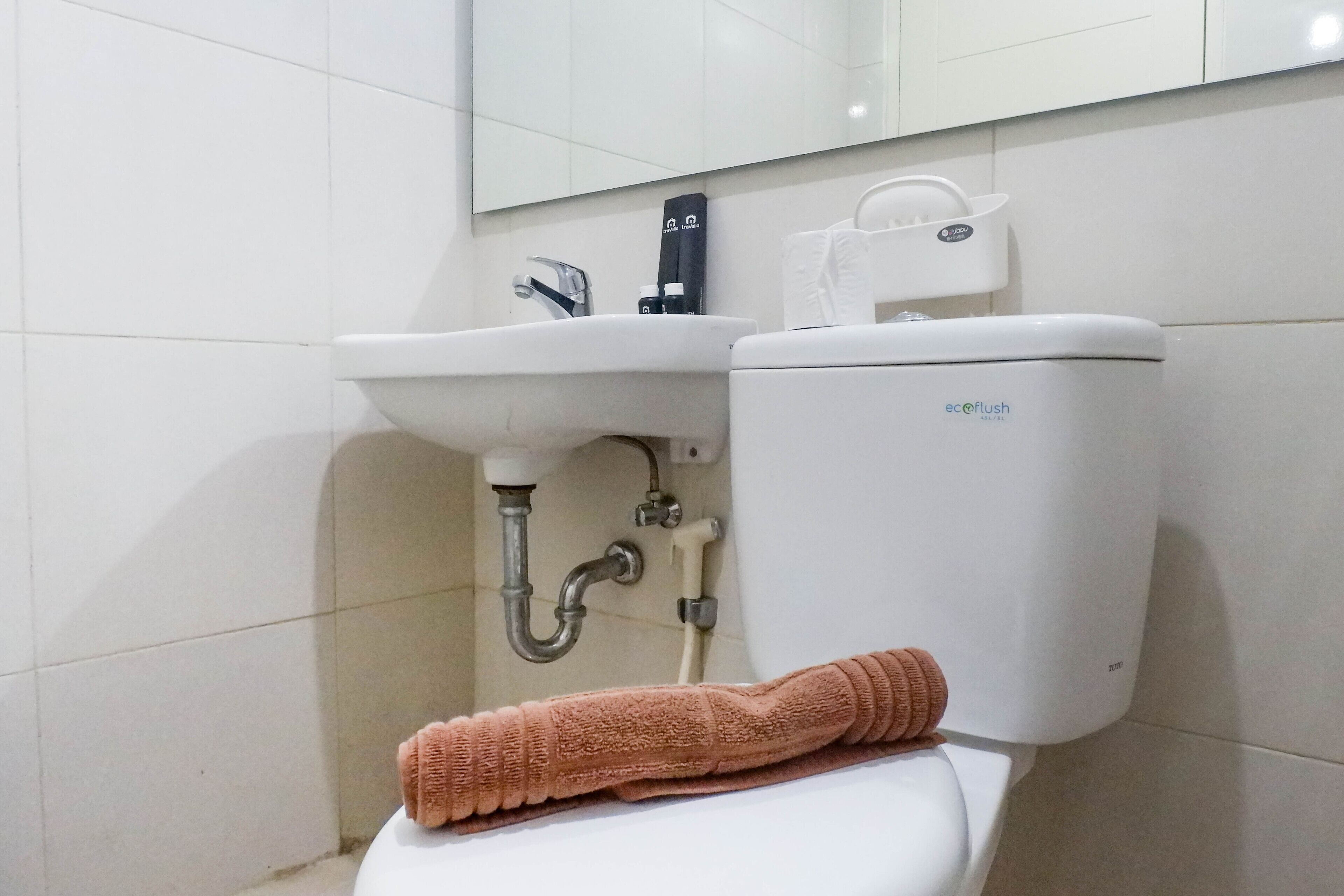 Ein Badezimmer mit einem weißen Waschbecken, einer Toilette und einem Handtuch auf dem Toilettensitz.