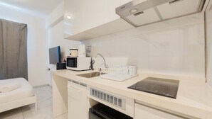 A compact kitchenette with a microwave, coffee maker, and a sink. - Simple And Cozy Stay Studio Sky House Alam Sutera Apartment (Tangerang)