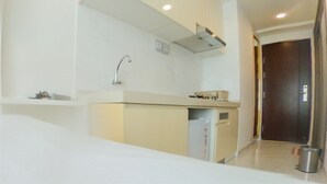 A modern kitchen with a built-in oven, a sink, and a microwave. There is a small trash bin and a door leading to another room. - Relaxing Studio At Sky House Bsd Apartment (Pagedangan)