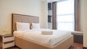 A neatly made bed with white linens, a bedside table with drawers, and a window with curtains.