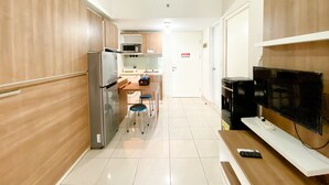 Una cocina compacta con refrigerador, microondas y un pequeño comedor con taburetes.