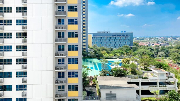 Un edificio de gran altura con múltiples balcones y una zona de piscina.