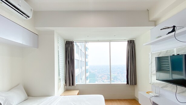 Ein Hotelzimmer mit einem großen Bett, einem Fernseher und Blick auf die Stadt durch ein Fenster.